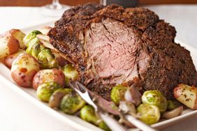 Prime rib roast surrounded by brussels sprouts and red potatoes