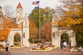 People walking through the stone Sample Gates at Indiana University in Bloomington