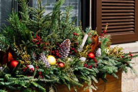 Winter window box with sprays of winterberries and tiers of noble fir, Scotch pine, southern magnolia and English variegated boxwood