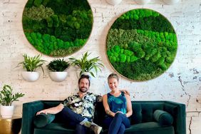 Couple behind Planthropy seated on green velvet sofa with botanical art in background