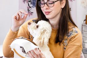 Michelle Staub doing embroidery with dog on lap