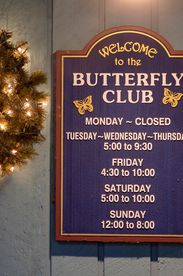 the butterfly club sign with hours